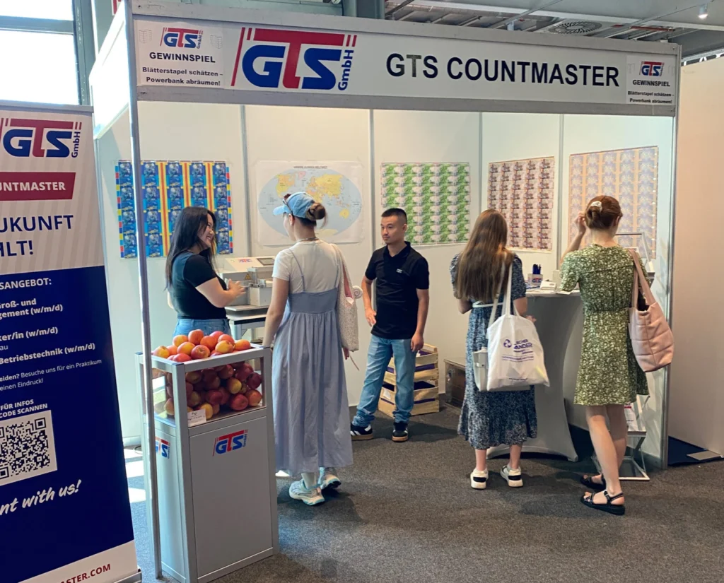 GTS Messestand auf der Bildungsmesse 2026 in Heilbronn. Drei Besucher werden von zwei GTS Auszubildenden über das Thema Ausbildung bei GTS beraten.
